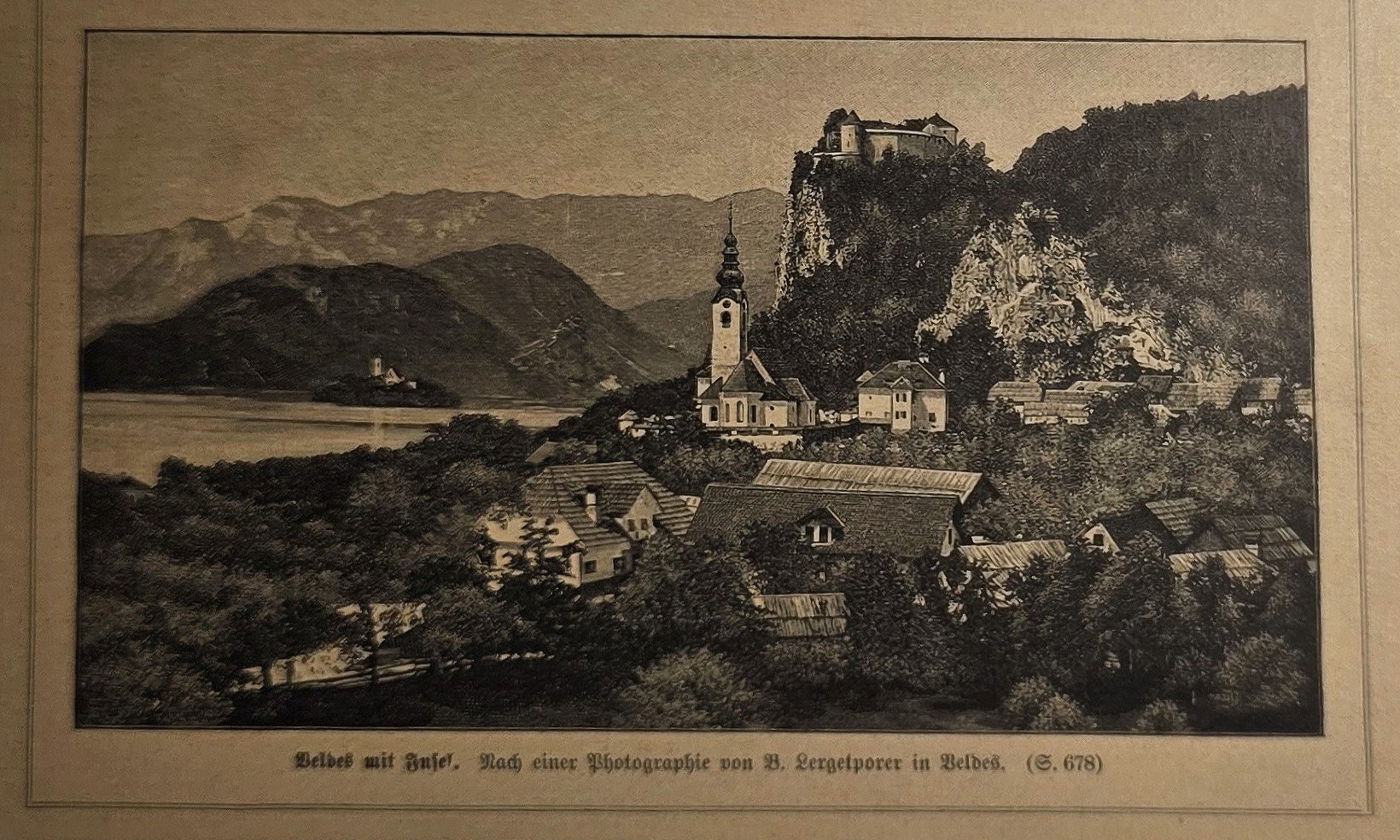 Ort am See mit Kirche und bewaldeten Höhen