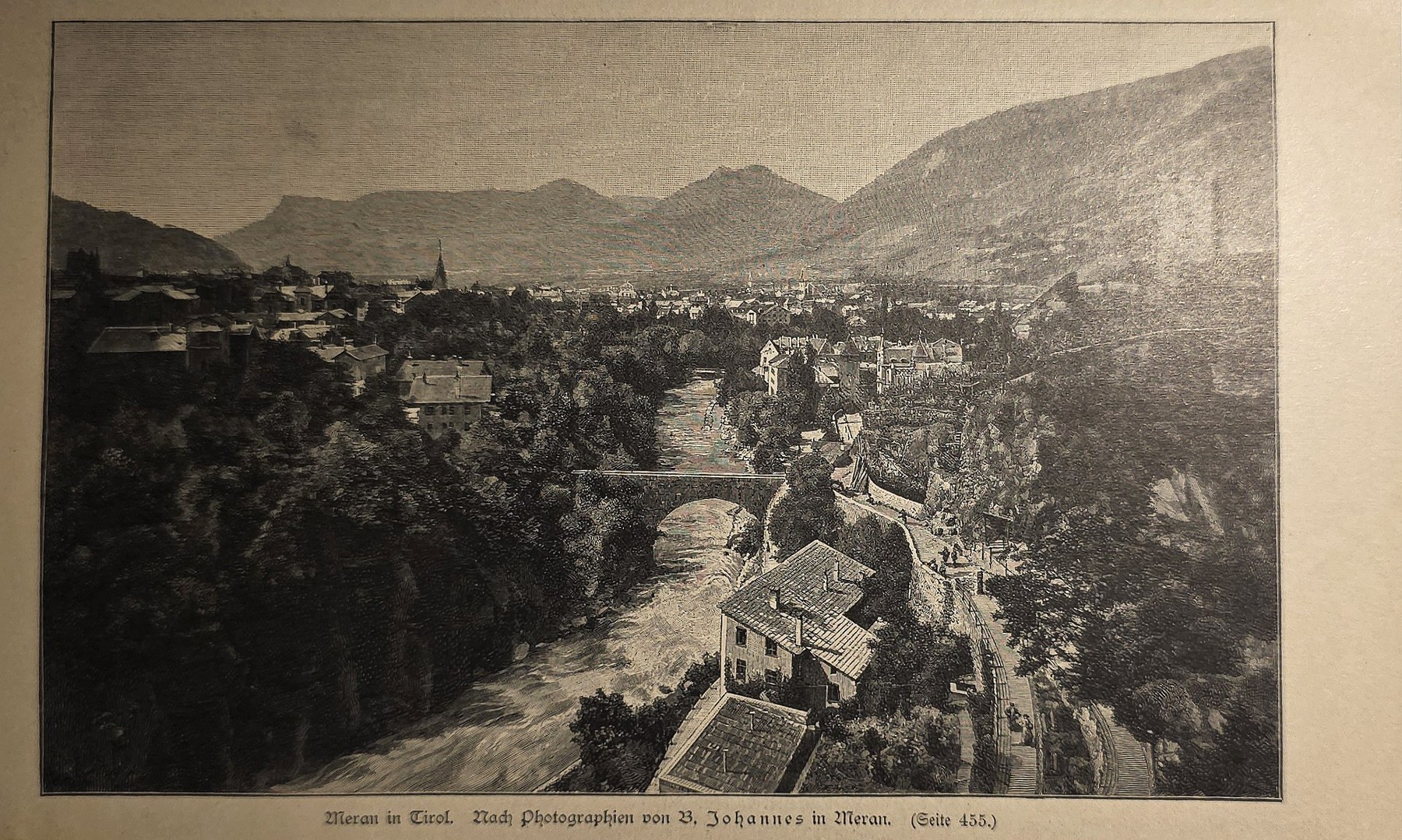 Stadtansicht im Tal mit Brücke und Bergen