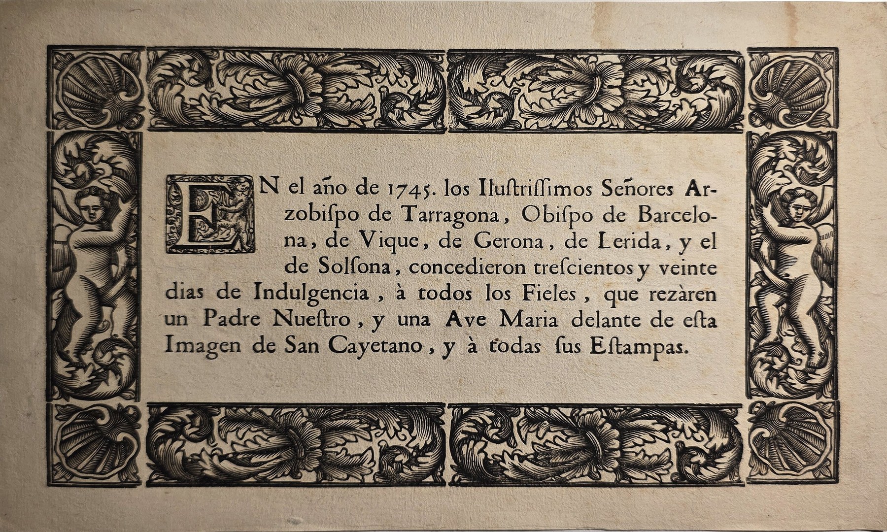 Alte Schriftgrafik mit großer Initiale und figürlichem Ornamentrahmen
